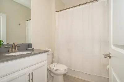 a white bathroom with a toilet and a sink at 2776LO VILLA 5 BED/5 BA (SANITIZED) in Kissimmee