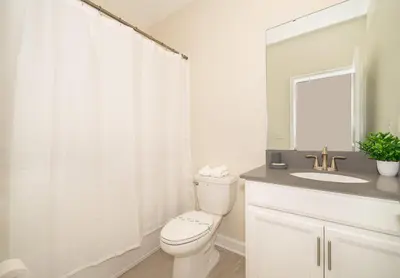 a bathroom with a toilet and a sink and a mirror at 2776LO VILLA 5 BED/5 BA (SANITIZED) in Kissimmee