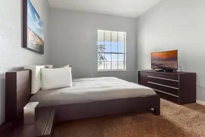 a bedroom with a bed with a dresser and a television at Vista Cay in Orlando
