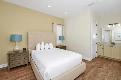 a white bedroom with a large white bed and a kitchen at Sunny Cottage Near Disney With Margaritaville Resort & Island H2O Access - 8032Ls in Orlando