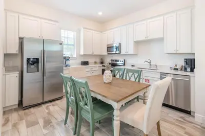 a kitchen with a wooden table and a refrigerator at Blue Shores Cottage Near Disney With Margaritaville Resort & Island H2O Access - 8079Kd in Orlando