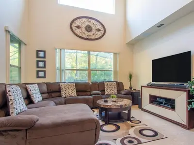 a living room with a couch and a flat screen tv at Luxurious With Privacy In 5 Bedroom With Private Pool By Florida Dream Homes in Kissimmee