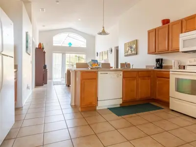 a kitchen with wooden cabinets and a tile floor at 4 Bed And 3 Bath In Perfect Location With Pool By Florida Dream Home in Kissimmee