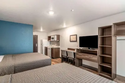 a bedroom with a bed and a desk with a television at WoodSpring Suites Sanford North I-4 Orlando Area in Sanford