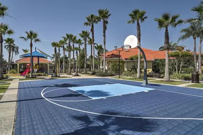 a basketball court in front of a house with palm trees at 8 Mi to Disney Villa with Screened Pool and Lanai in Kissimmee