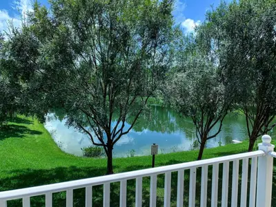 a white fence next to a lake with trees at Crystal Villa in Kissimmee