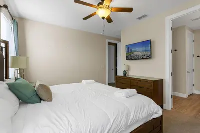 a bedroom with a large white bed with a ceiling fan at 520-IBRAHIM · 520 - 8BD Home PoolSpa - MovieGame room in Orlando