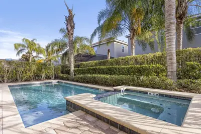 a swimming pool in a yard with palm trees at 520-IBRAHIM · 520 - 8BD Home PoolSpa - MovieGame room in Orlando