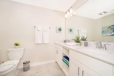 a white bathroom with a toilet and a sink at 3180-202BV STOREY LAKE, CONDO 2/2 GARDEN VIEW in Kissimmee