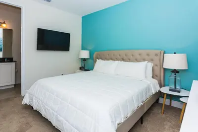 a bedroom with a large white bed with a blue wall at Gorgeous Single Home with Private Pool at Encore in Orlando