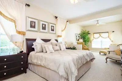a bedroom with a large bed and a chair at Mickeys Floridian - Glorious 5BR Private South Facing Pool Hot Tub Game RM GYM BBQ - 2 miles to Disney in Orlando