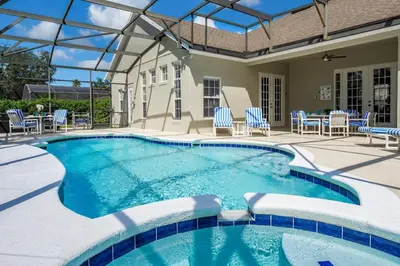 a swimming pool with chairs and a patio with a table at Mickeys Floridian - Glorious 5BR Private South Facing Pool Hot Tub Game RM GYM BBQ - 2 miles to Disney in Orlando