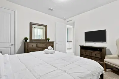 a white bedroom with a large bed and a flat screen tv at 320 Pet Friendly 6BD Villa - PoolSpa in Orlando