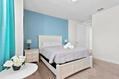 a bedroom with a white bed and a blue wall at 320 Pet Friendly 6BD Villa - PoolSpa in Orlando