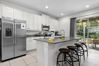 a kitchen with a stainless steel refrigerator and bar stools at 320 Pet Friendly 6BD Villa - PoolSpa in Orlando