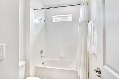 a white bathroom with a shower and a toilet at Family Resort - 6BR Mansion - Private Pool, Home Theater, BBQ and More in Kissimmee