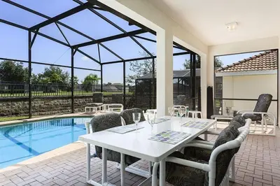 a white table and chairs next to a swimming pool at bsv_villa7747 in Orlando