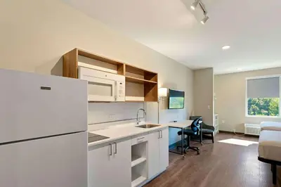 a kitchen with a white refrigerator and a dining room at Extended Stay America Premier Suites - Orlando - Sanford in Sanford