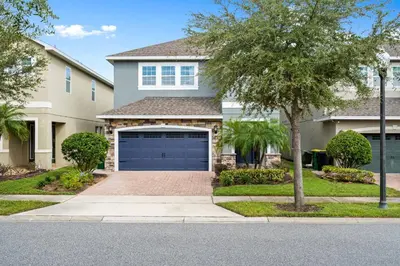 a house with a garage and a tree at Encore Resort 6 Bedroom Home with Pool 2301 in Orlando