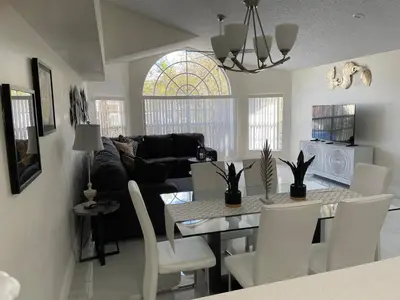 a kitchen and living room with a table and chairs at ELEGANT & LUXURIOUS FAMILY APARTMENT close to DISNEY WORLD in Kissimmee