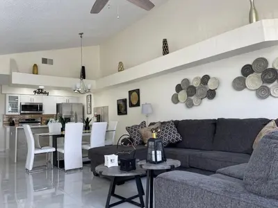 a living room and kitchen with a couch and tables at ELEGANT & LUXURIOUS FAMILY APARTMENT close to DISNEY WORLD in Kissimmee