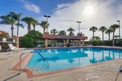 a large swimming pool in a resort with palm trees at Steps to Pool Winter Garden House with Lanai! in Orlando