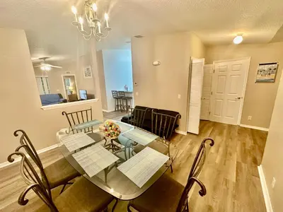 a dining room and living room with a table and chairs at Grand Holiday 3BR Palms Condo near Disney Parks in Kissimmee