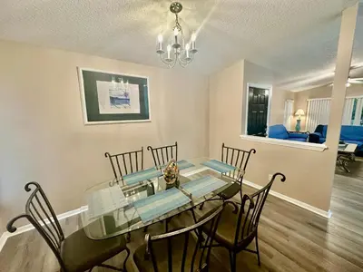 a dining room with a glass table and chairs at Grand Holiday 3BR Palms Condo near Disney Parks in Kissimmee