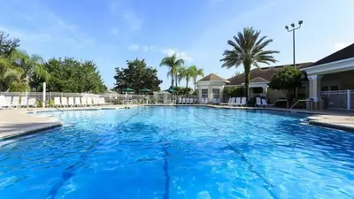 a large blue swimming pool with palm trees and houses at Immaculate 4 bedrooms 3 bathroom in Windsor Palms villa in Kissimmee