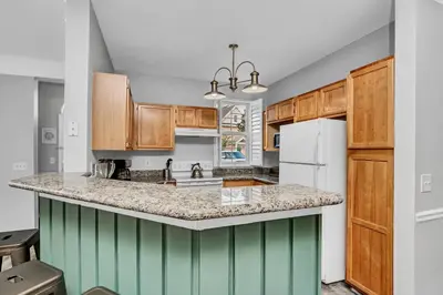 a kitchen with wooden cabinets and a white refrigerator at 2 Bedroom Vacation Condo 2016 in Kissimmee