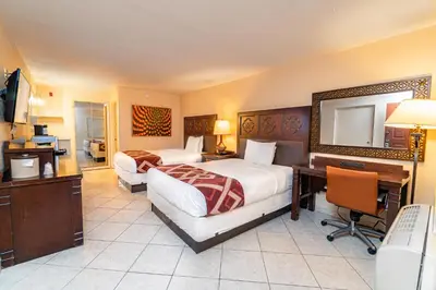 a hotel room with two beds and a desk and a computer at Sevilla Inn Kissimmee- Near Disney in Kissimmee