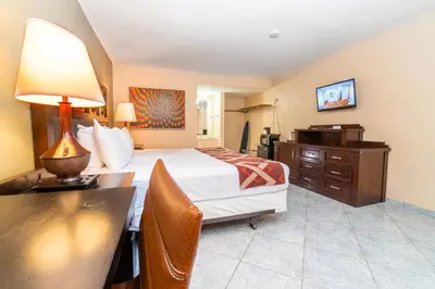 a hotel room with a bed and a desk with a lamp at Sevilla Inn Kissimmee- Near Disney in Kissimmee