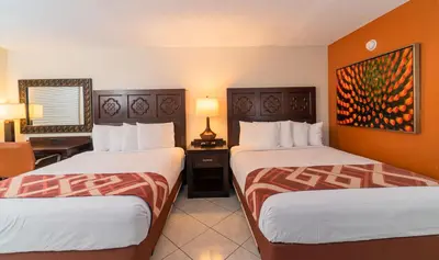 a hotel room with two beds and a desk at Sevilla Inn Kissimmee- Near Disney in Kissimmee