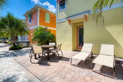 a patio with a table and chairs next to a building at Sunny Yellow Cottage Near Disney With Margaritaville Resort Access & Island H20 Waterpark - 3075Kl in Orlando