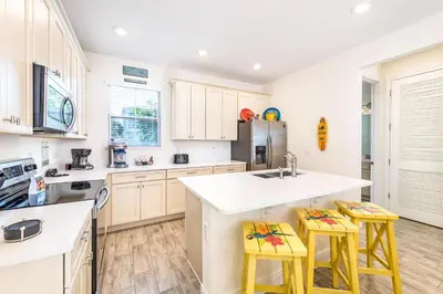 a kitchen with white cabinets and yellow stools at Love, Luck And Magic Cottage With Private Hot Tub Near Disney And Margaritaville Resort & Island H2O Access - 8013Ff in Orlando
