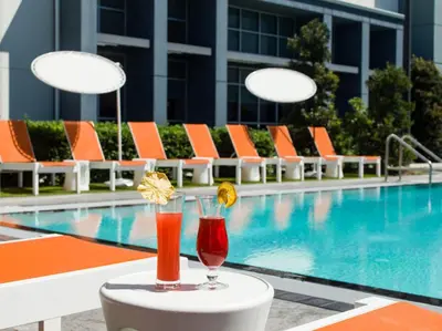 two cocktails on a table next to a swimming pool at Aloft Orlando International Drive by Marriott in Orlando