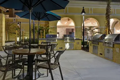a patio with a table and chairs and an outdoor kitchen at Home2 Suites By Hilton Orlando Flamingo Crossings, FL in Orlando