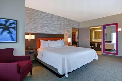 a bedroom with a large bed and a red chair at Home2 Suites By Hilton Orlando Flamingo Crossings, FL in Orlando