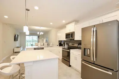 a kitchen with white cabinets and a stainless steel refrigerator at High end apartment in luxurious Storey Lake community Next to Disney! in Kissimmee