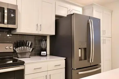 a kitchen with white cabinets and a stainless steel refrigerator at High end apartment in luxurious Storey Lake community Next to Disney! in Kissimmee