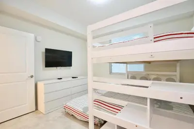 a bedroom with two bunk beds and a flat screen tv at High end apartment in luxurious Storey Lake community Next to Disney! in Kissimmee
