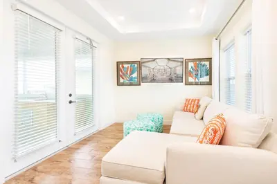 a living room with a white couch and windows at Toes In The Water Cottage With Private Pool Near Disney With Margaritaville Resort & Island H2O Access - 8008Sh in Orlando