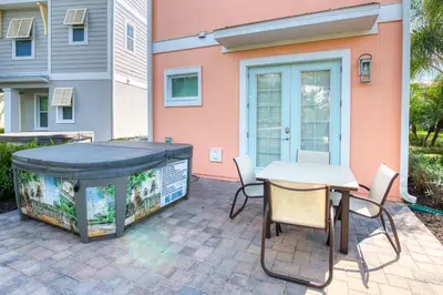 a patio with a large hot tub and a table and chairs at Comfy Cottage With Hot Tub Near Disney With Margaritaville Resort & Island H2O Access - 8029Sb in Orlando
