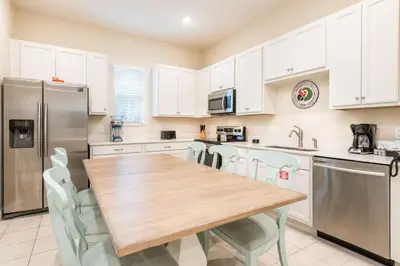 a kitchen with a wooden table and appliances at Comfy Cottage With Hot Tub Near Disney With Margaritaville Resort & Island H2O Access - 8029Sb in Orlando