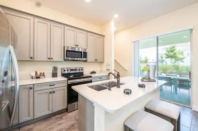a kitchen with a sink and a refrigerator at Bright & Airy Cottage Near Disney With Margaritaville Resort & Island H2O Access - 8008Ls in Orlando