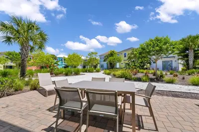a patio with a table and chairs and palm trees at Dreamy Cottage Near Disney With Margaritaville Resort & Island H2O Access - 8069Kd in Orlando