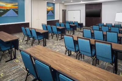 a conference room with tables and chairs and a screen at Hampton Inn Kissimmee North in Kissimmee