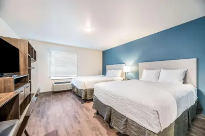 a hotel room with two beds and a flat screen tv at Extended Stay America Select Suites - Orlando - Kissimmee in Orlando