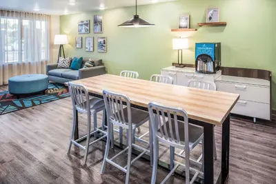 a living room with a large wooden table and chairs at Extended Stay America Select Suites - Orlando - Kissimmee in Orlando