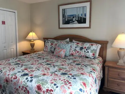 a bedroom with a bed with a floral bedspread and two lamps at Gated Emerald island resort townhome, Overlook Pool, 3 miles to Disney, rent by owner in Kissimmee